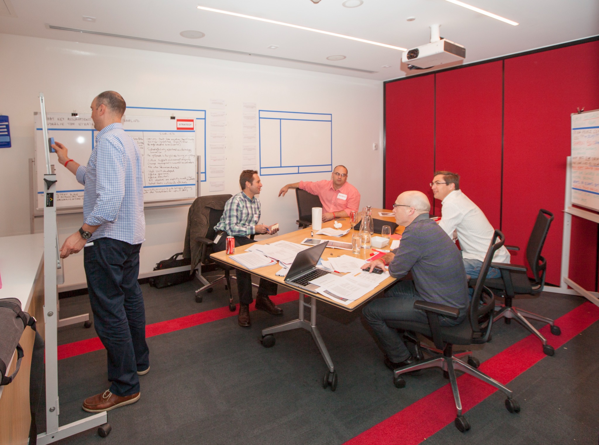 A facilitator and leadership team working together around large visible planning boards during a Fundamental Academy session