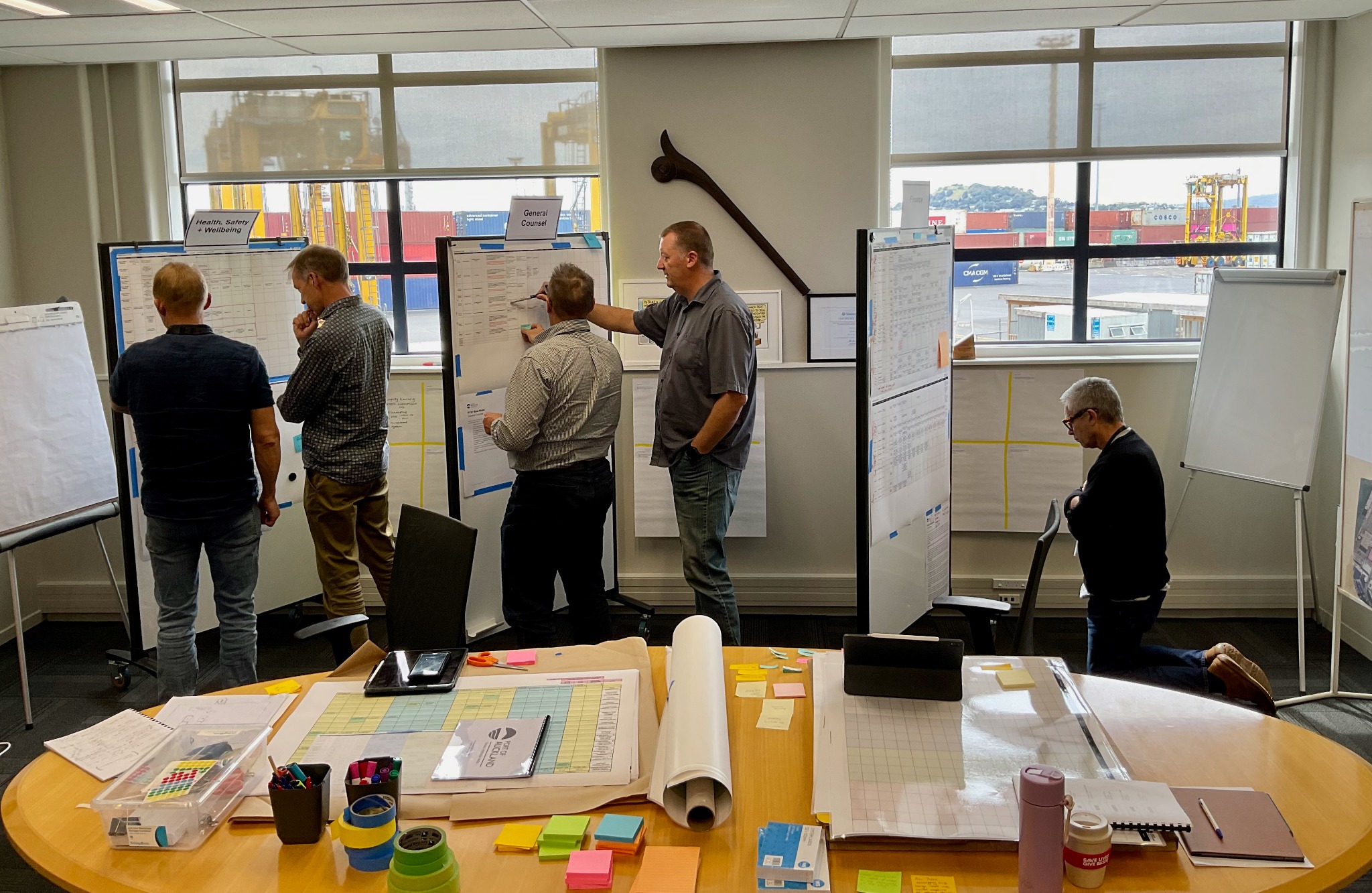 James facilitating a leadership team working across wall-sized enterprise frameworks overlooking the port